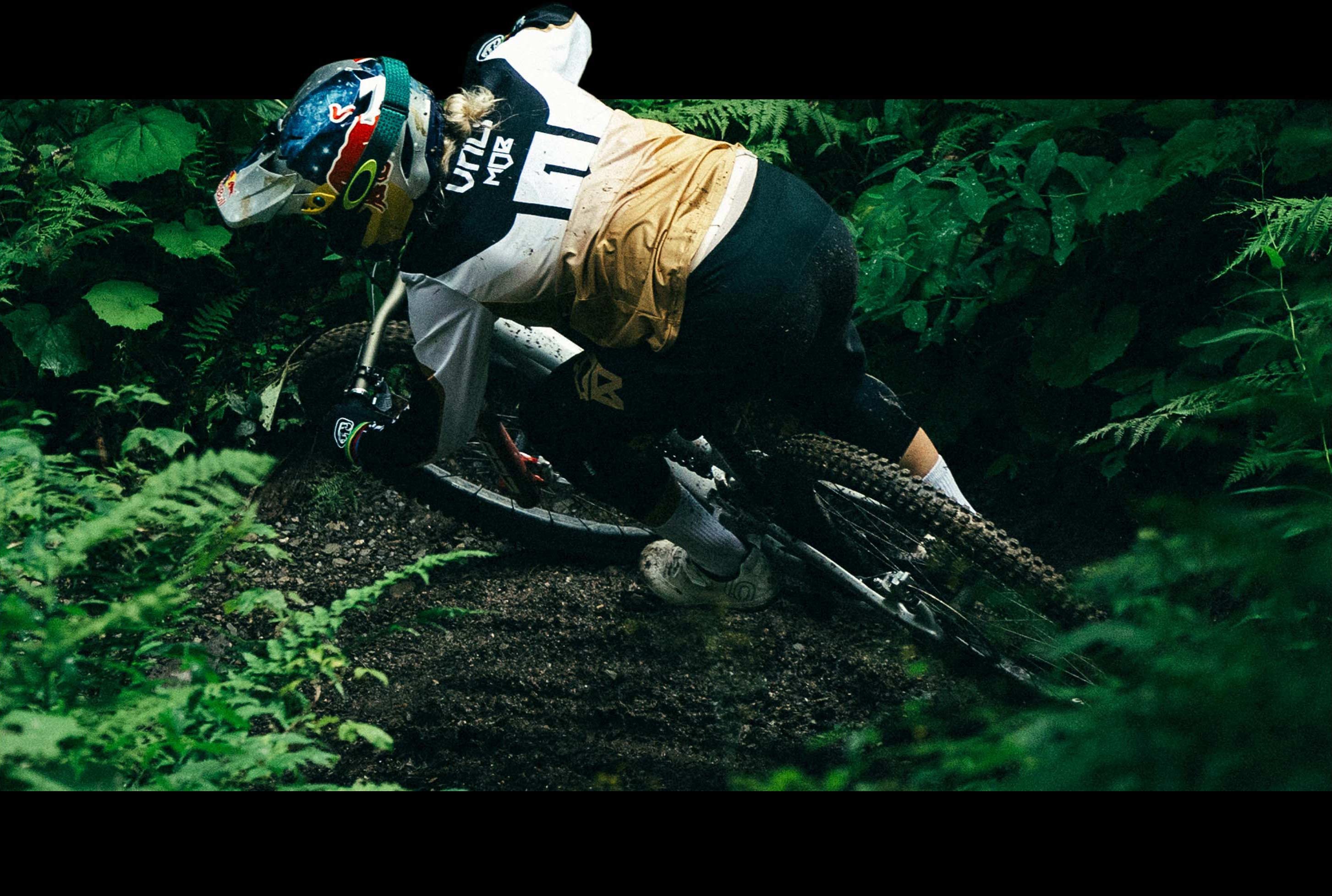 Overhead shot of Vali riding her bike through the dark green of the forest.